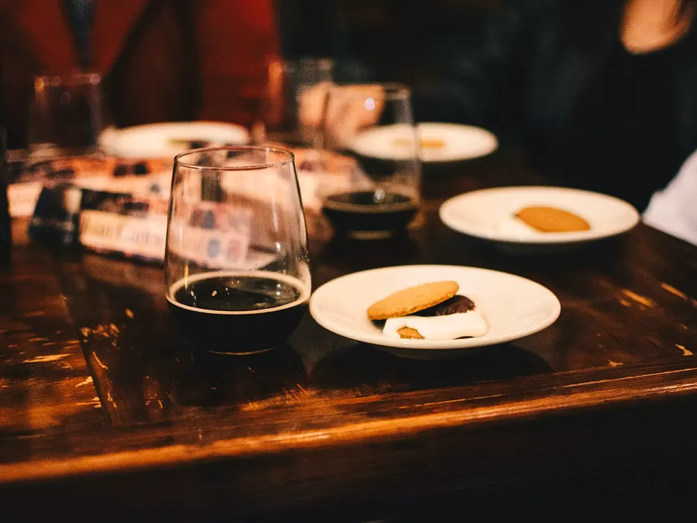 Tavolo di legno a fine cena, con calici di vino rosso e piatti quasi vuoti.